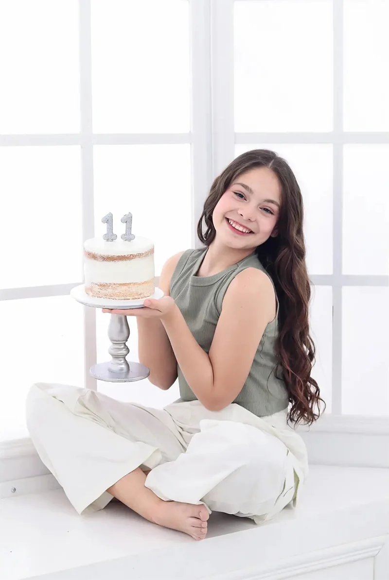 Niña sentada en el piso con una torta de cumpleaños