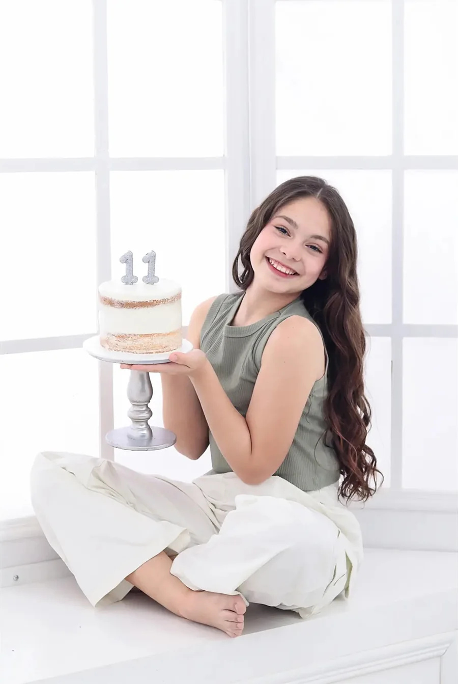 Niña sentada en el piso con una torta de cumpleaños