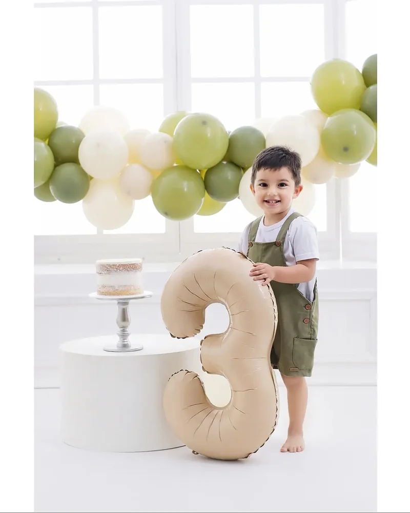 Niño junto a un globo del número tres y una torta